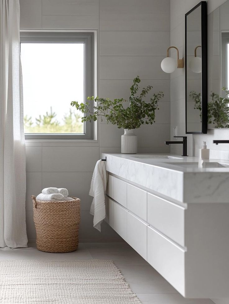 Minimalist bathroom with floating white bathroom cabinets, marble countertop, black faucet, wall mirror, and woven basket with towels