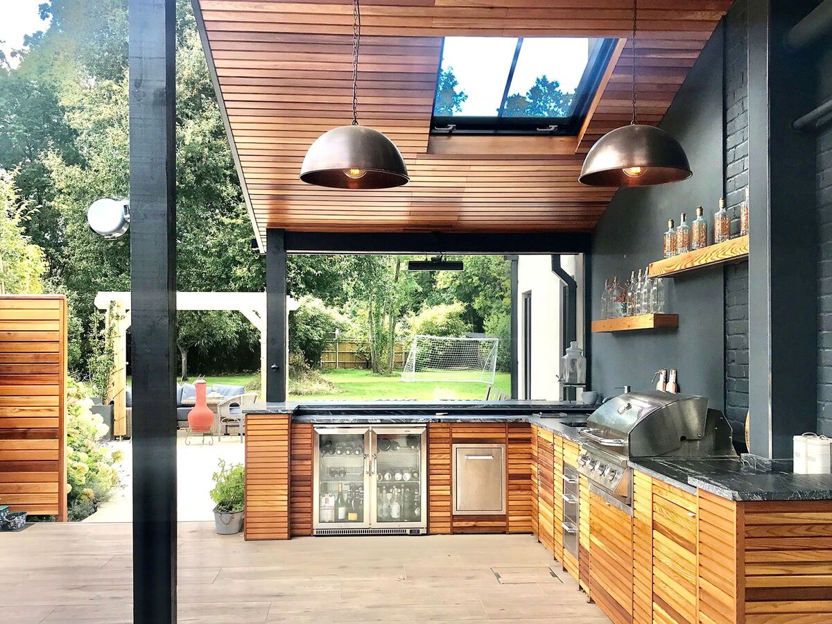 Modern Outdoor RTA Cabinets in Canada with stainless grill, beverage fridge, and stylish wood paneling under a skylight patio