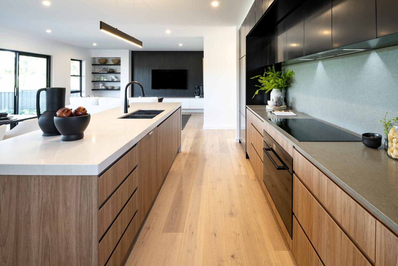 Modern kitchen with wood cabinets in polyurethane (PU) finish and black matte accents, featuring a large island and minimalist design