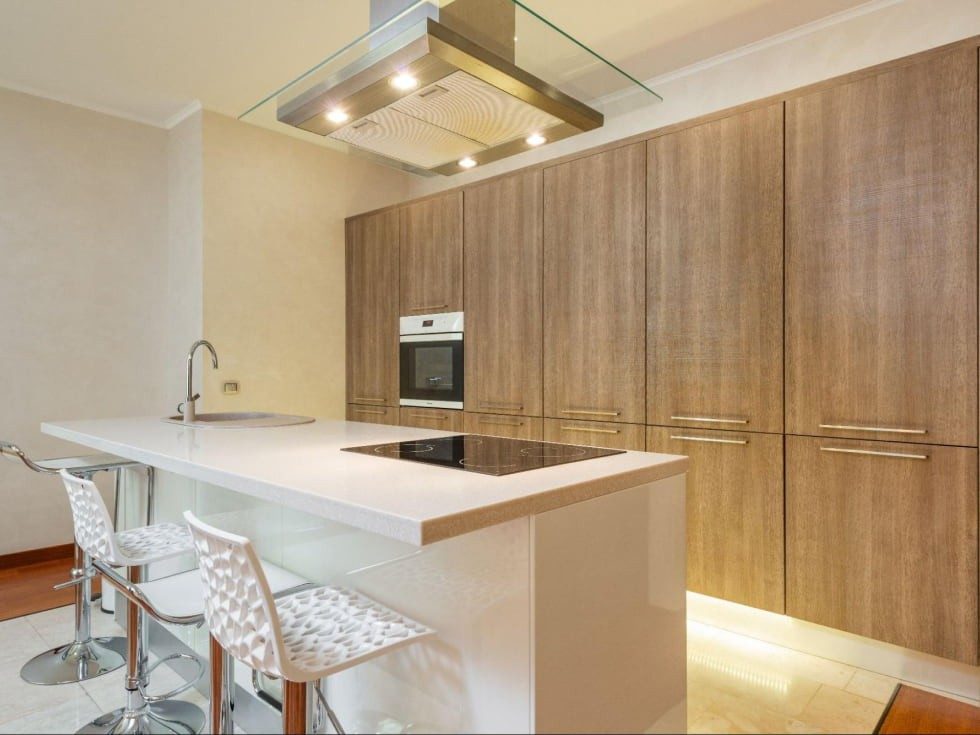 Modern kitchen with tall engineered wood Canada cabinets and white island countertop