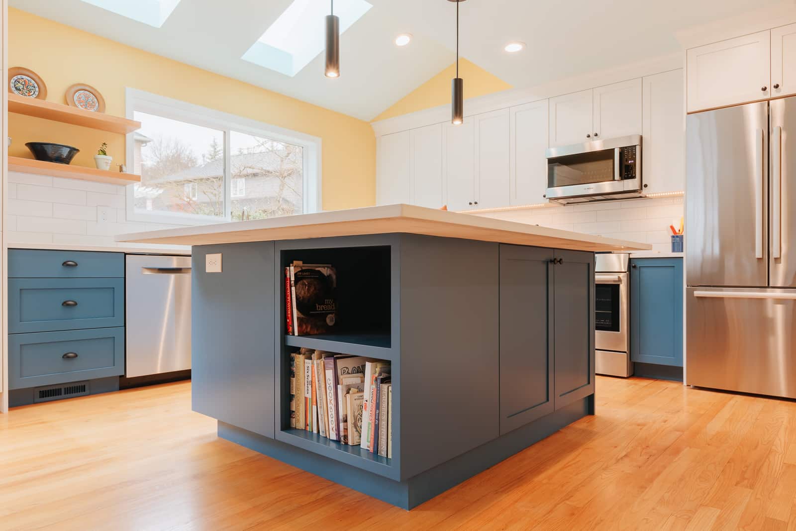 Bright modern kitchen with blue island and white cabinets showcasing laminate vs veneer for cabinet surfaces