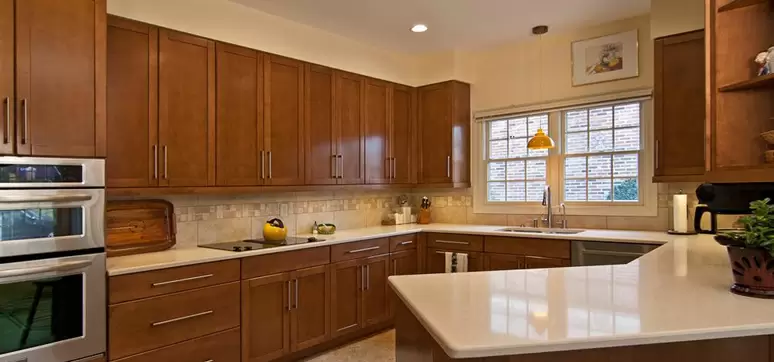 Countertop Materials for Engineered Wood Cabinets: warm L-shaped kitchen with engineered wood cabinets and light quartz countertop.