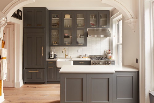 Cabinet color trends featuring elegant dark gray kitchen cabinets with brass hardware and white countertops.