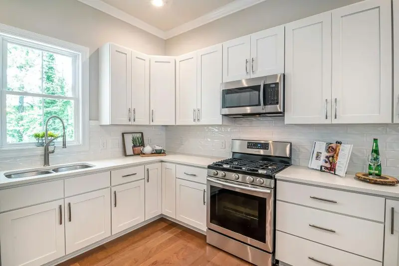 Navy blue shaker kitchen showcasing the History of RTA Cabinets with white island and brass hardware