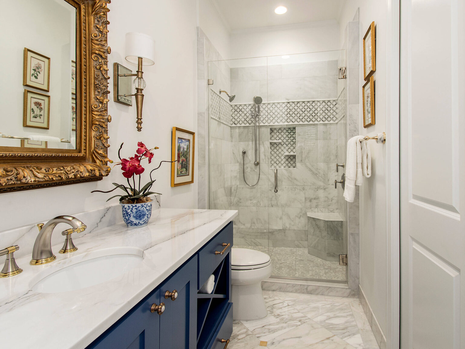 Elegant blue guest bathrooms cabinets with marble countertop and glass shower in a luxury home