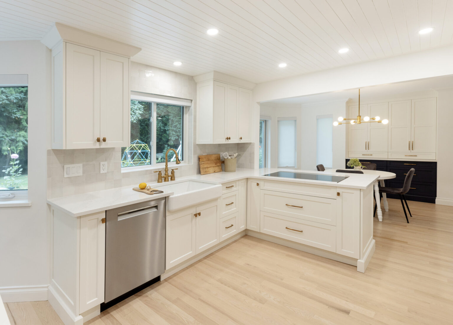 Bright modern Canadian kitchen with soft white shaker cabinets, brass hardware, quartz countertops, and light wood flooring, highlighting one of the best kitchen cabinet colors Canada.