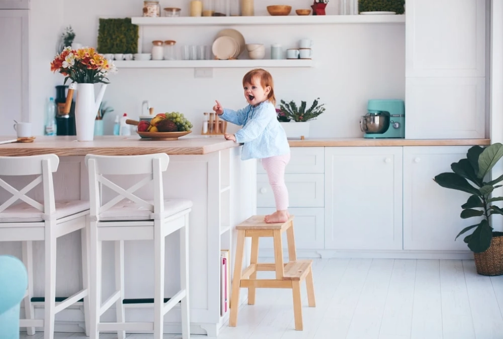 Childproofing RTA Cabinets: toddler on step stool at kitchen island with modern white cabinets