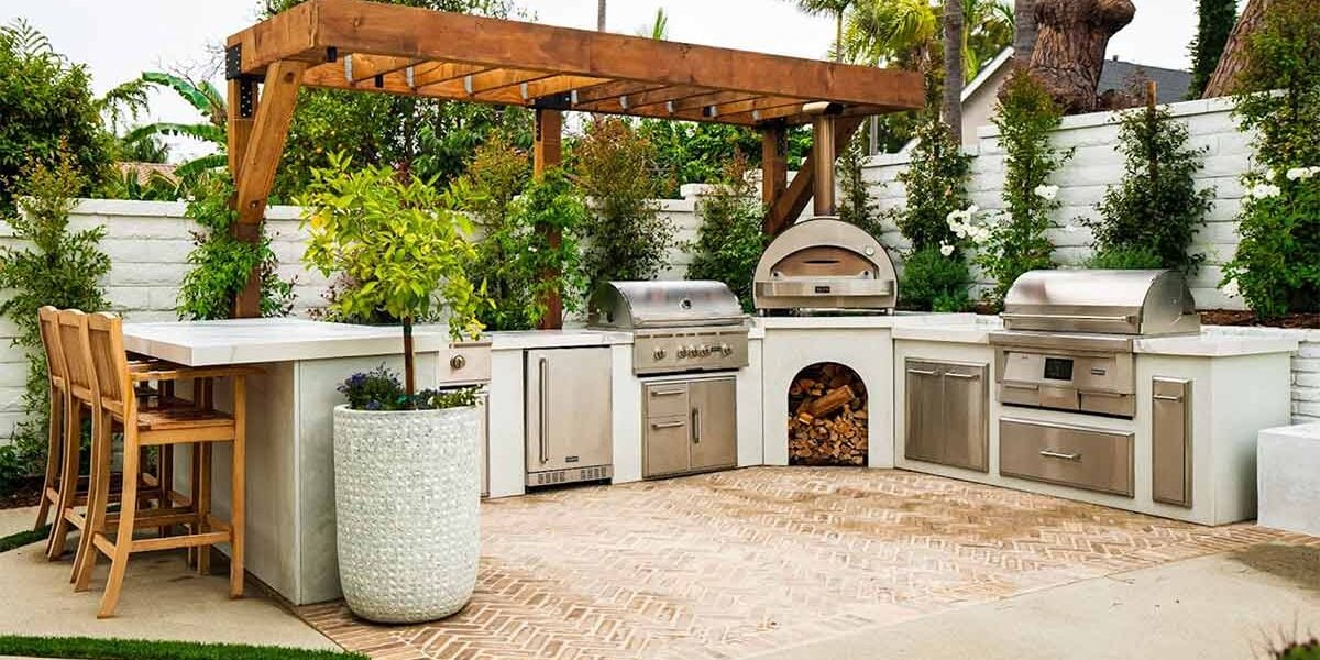 Outdoor kitchen with stainless appliances and weather-proof RTA cabinets under a wooden pergola