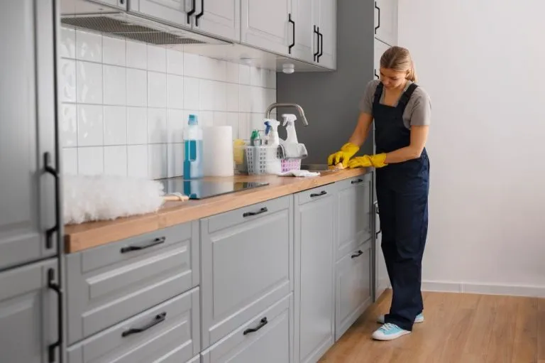 RTA cabinets maintenance in Canada: homeowner wiping gray kitchen cabinets with a microfiber cloth to keep finishes spotless