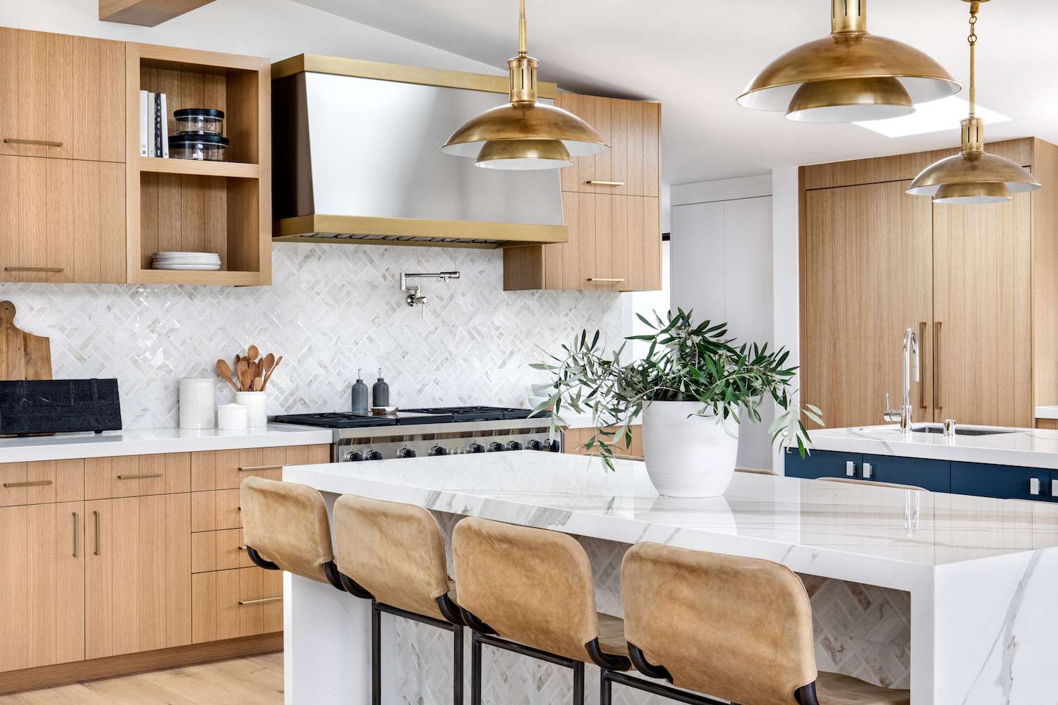 Modern Canadian kitchen with natural wood cabinets, marble island, and brass accents—showcasing one of the best kitchen cabinet colors Canada in 2025.