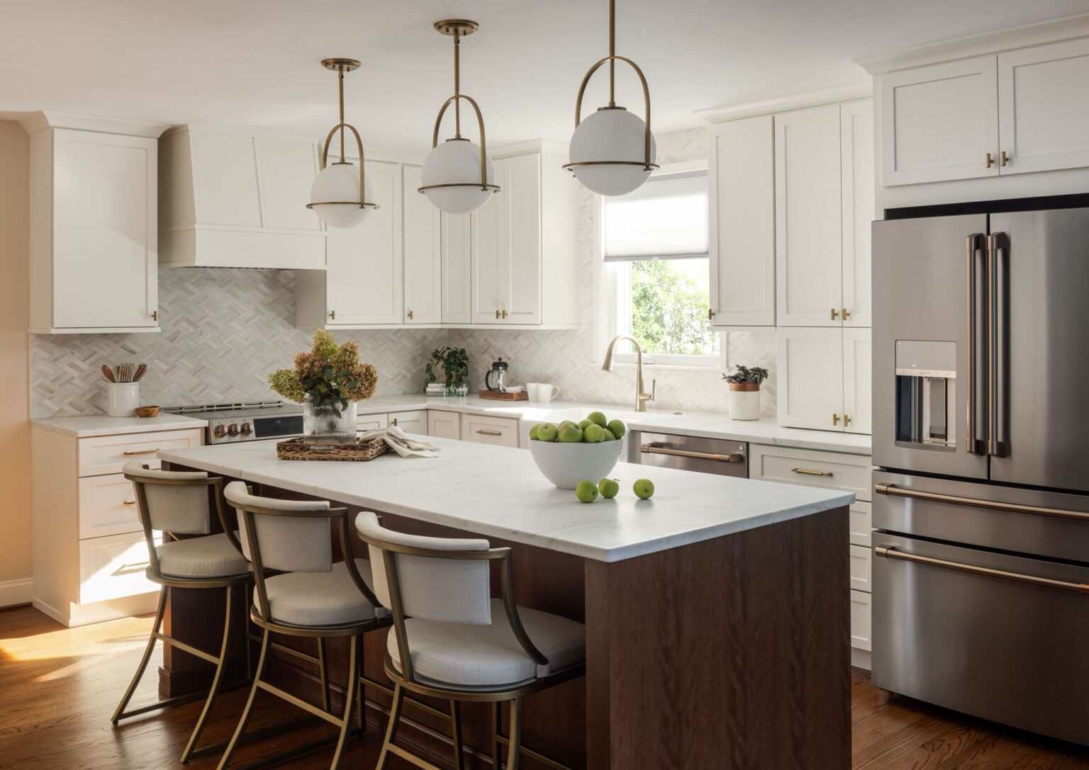 Bright kitchen with white shaker RTA cabinets, brass hardware, herringbone backsplash, wood island, and stainless French-door fridge.