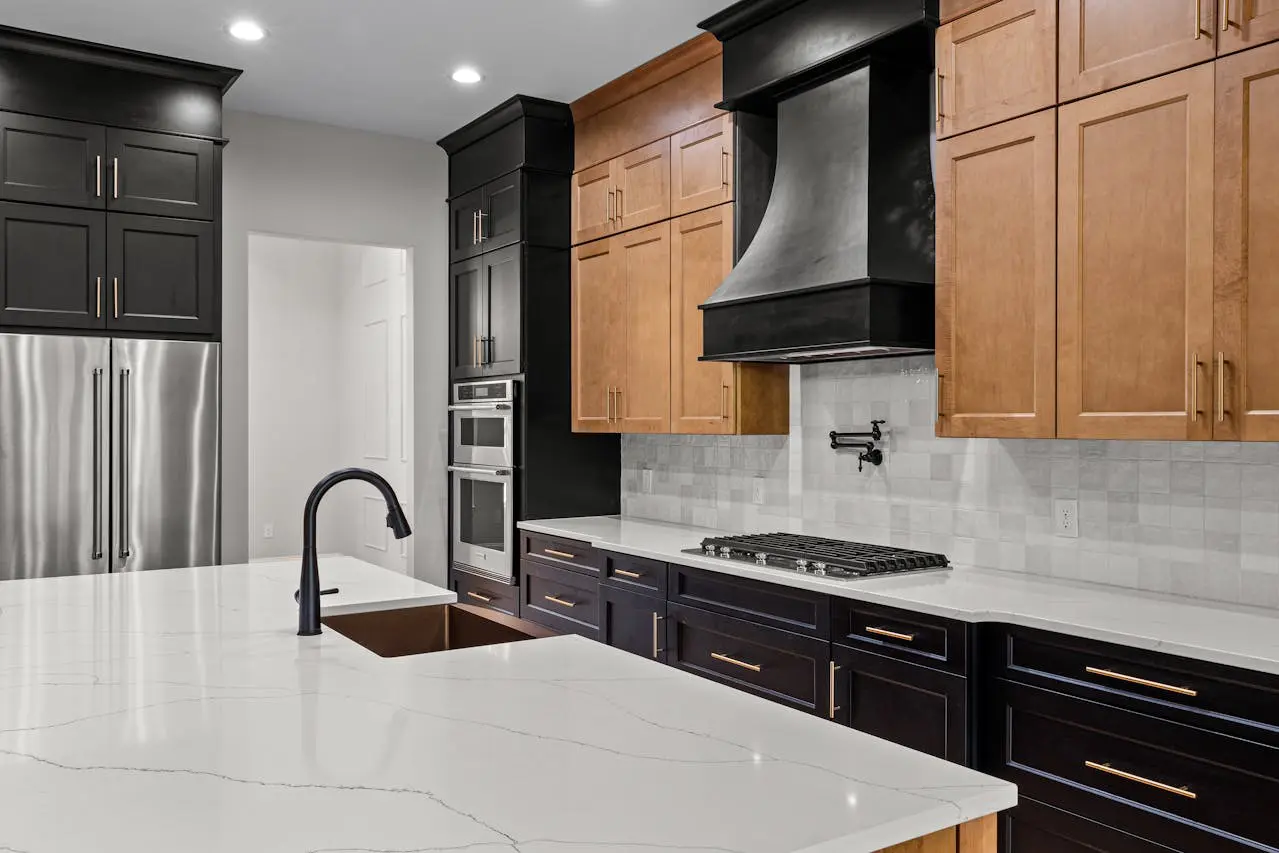 Modern Canadian kitchen featuring premium RTA cabinets in a two-tone black and natural wood finish, complemented by a sleek marble countertop and matte black fixtures.