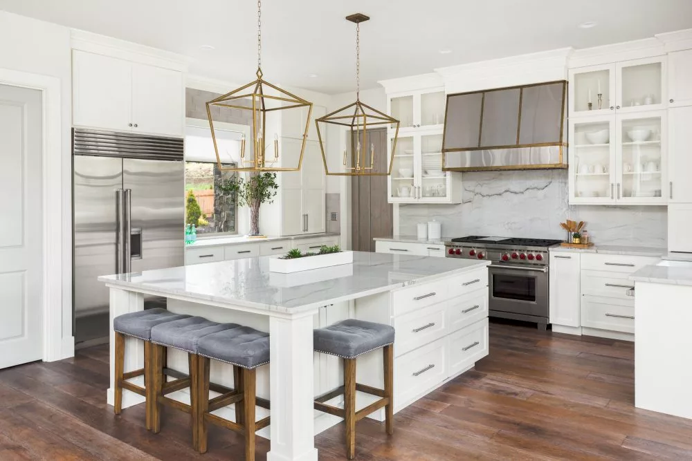 Bright modern kitchen in Canada featuring premium RTA cabinets with white shaker-style doors, marble countertops, and brass light fixtures for a timeless luxury look.