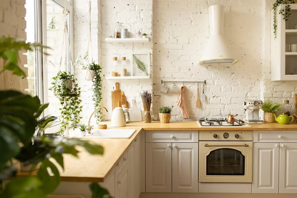 Bright eco-friendly kitchen with white kitchen cabinet fronts, wooden countertop and hanging plants by a large window