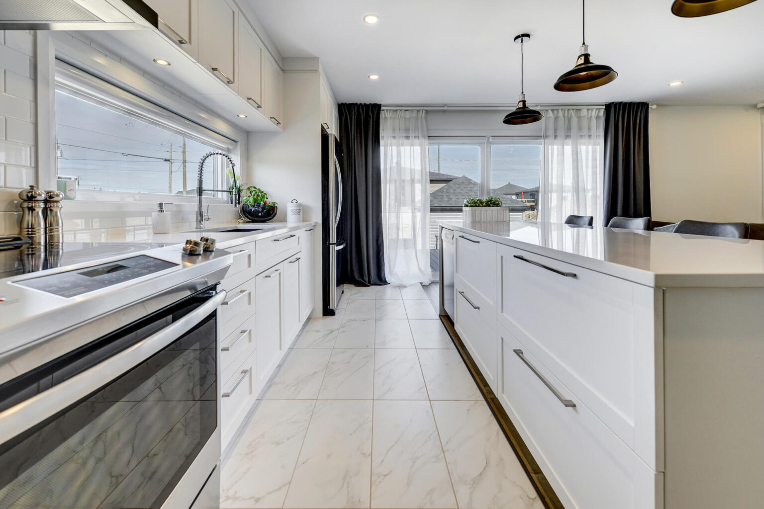 Modern white Shaker kitchen cabinets Montreal with quartz countertops, island drawers and black pendant lights