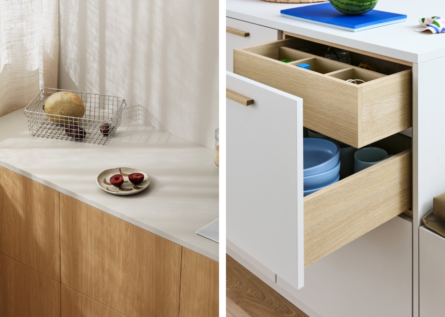 Close-up of modern kitchen cabinet with light wood fronts, soft white countertop, and organized pull-out drawers.