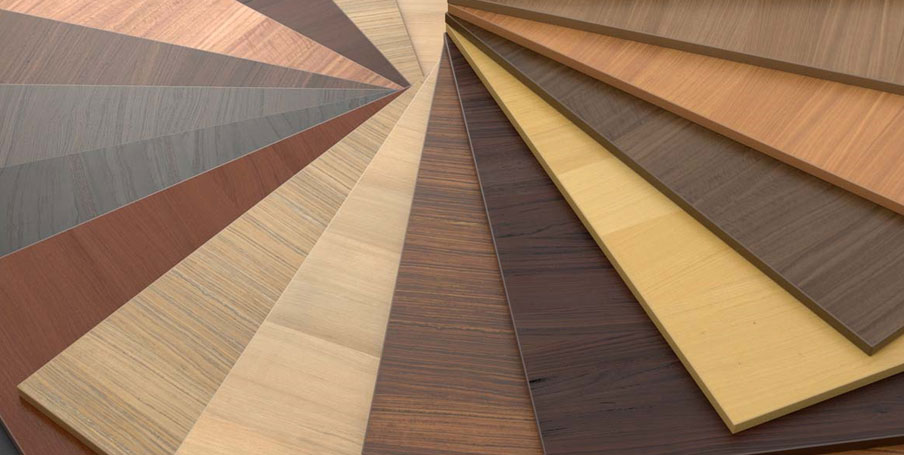 Fan of wood laminate and veneer samples in various colors and grains for modern kitchen cabinet finishes.