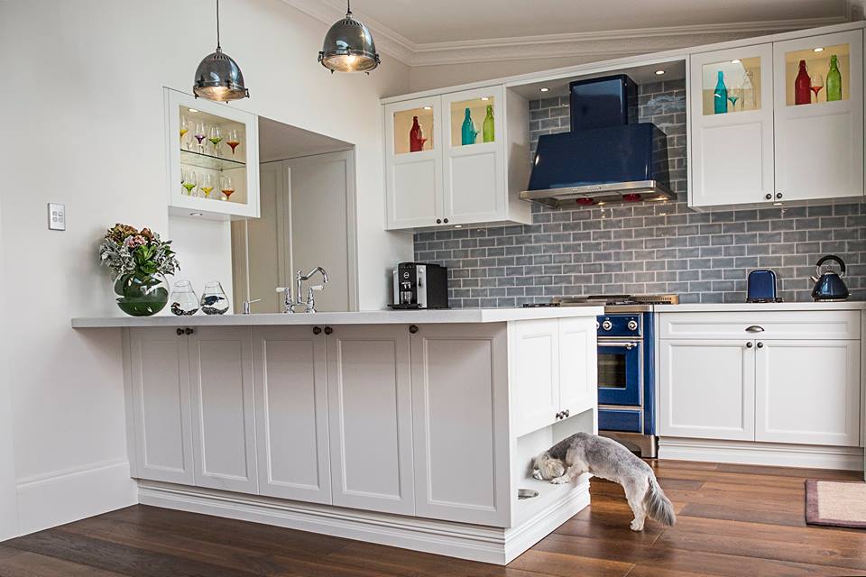 Pet-friendly kitchen cabinet design with built-in dog feeding station in white shaker island