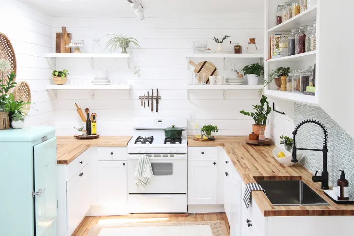 Bright white farmhouse-style kitchen with open shelving, butcher block countertops, and a black gooseneck faucet — Kitchen suppliers inspiration