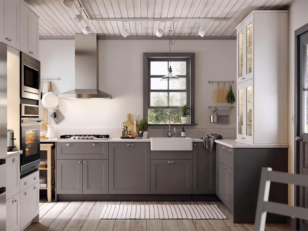 Modern two-tone kitchen with gray base cabinets, white tall cabinets, farmhouse sink, and stainless range hood from a Kitchen Cabinet Supplier.