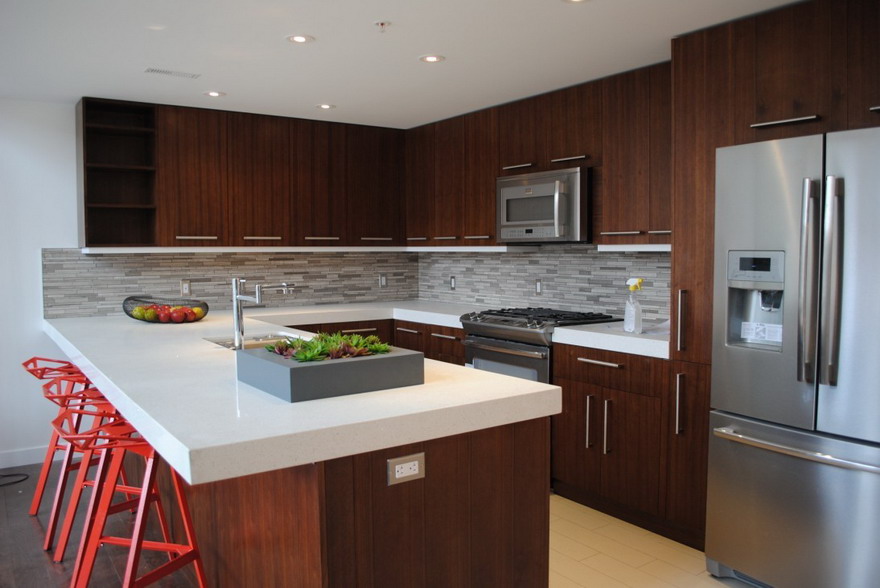 Modern Kitchen Cabinet Mississauga design featuring dark wood RTA cabinets, white quartz countertops, and red bar stools