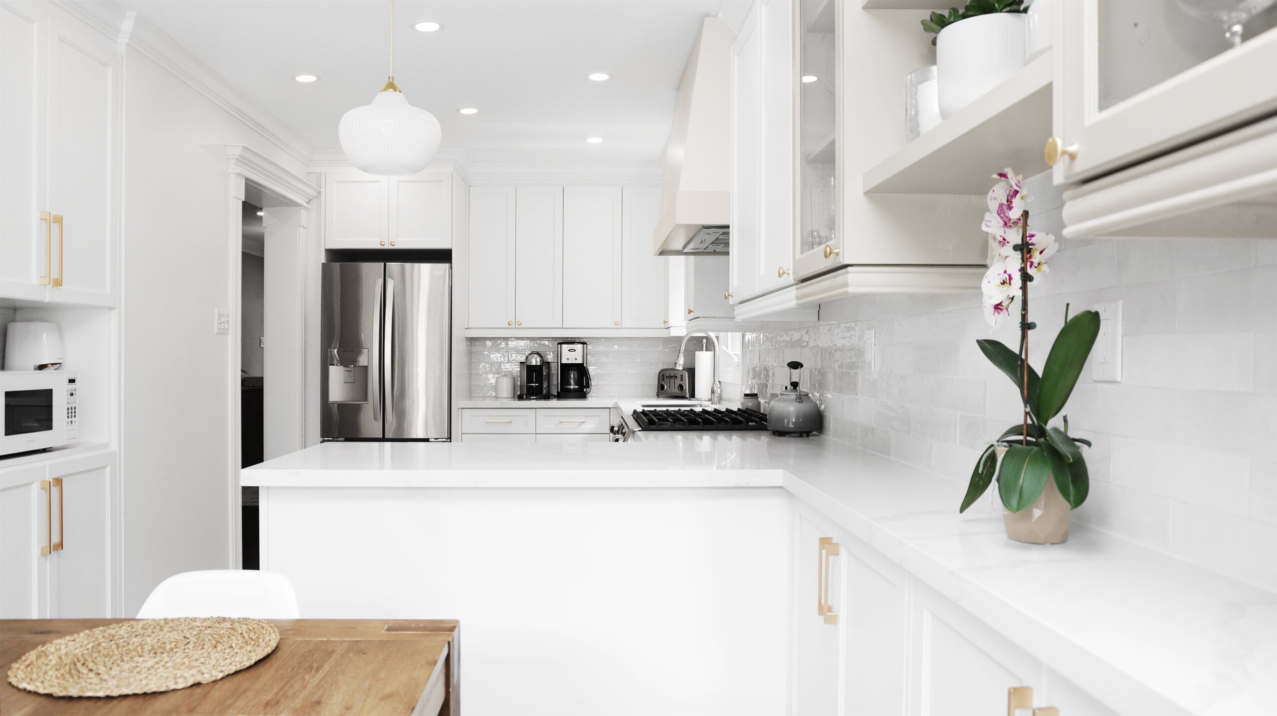 Kitchen cabinet design featuring white shaker cabinets with brass pulls, a quartz waterfall island, and a white subway tile backsplash.