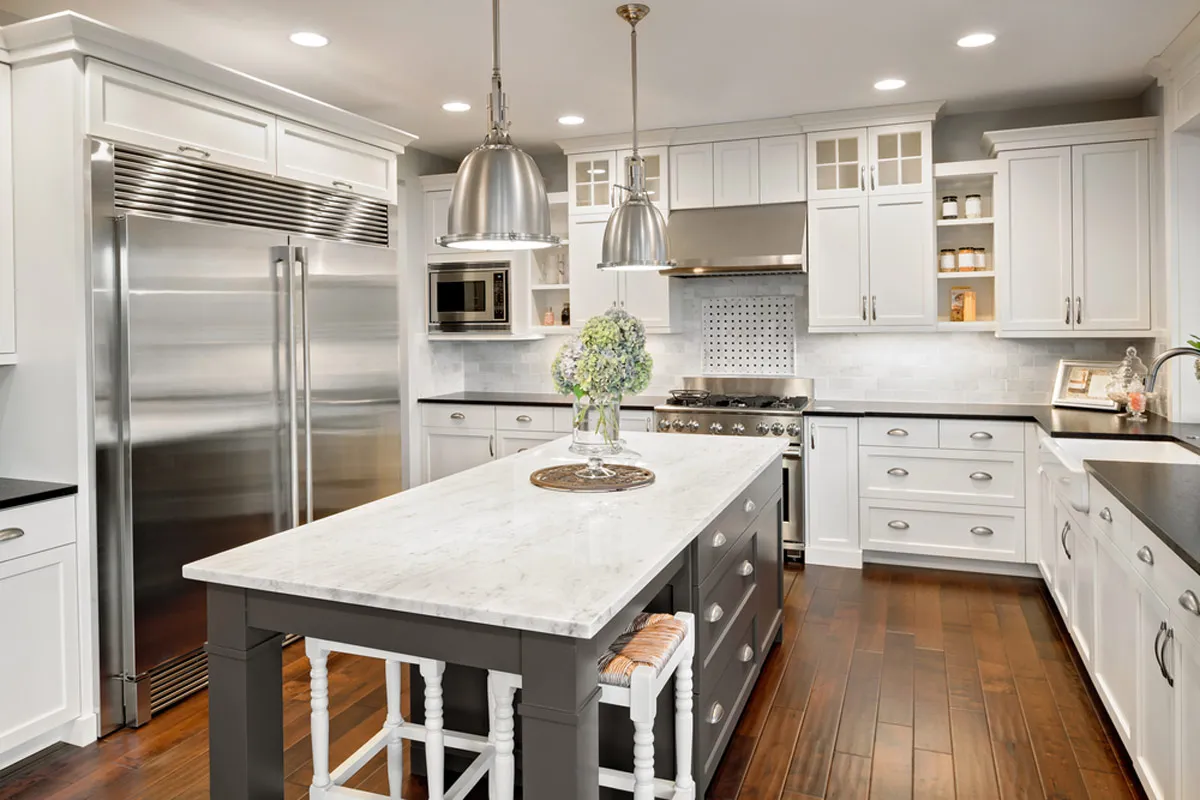 Premade kitchen cabinet set in a bright modern kitchen with white shaker doors, a gray island, and stainless appliances.