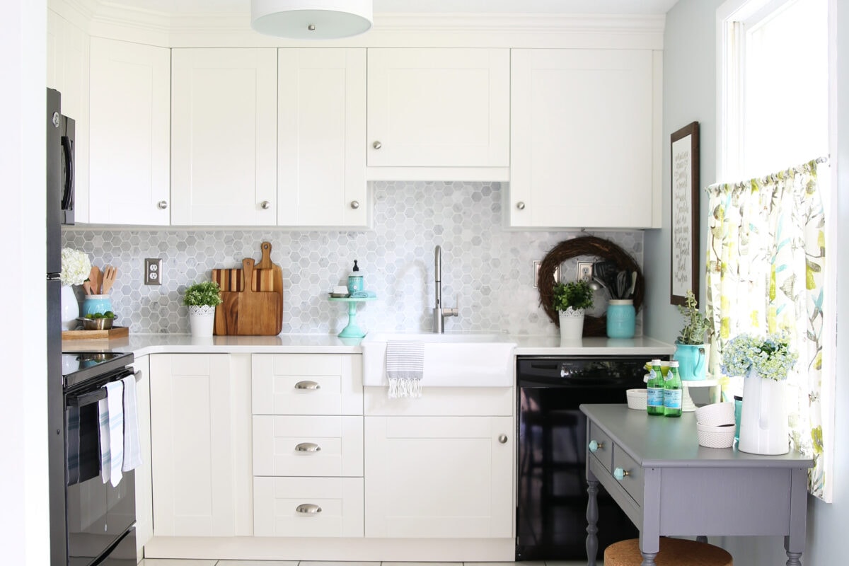 Bright white shaker premade kitchen cabinet set with hex tile backsplash and an apron-front farmhouse sink.