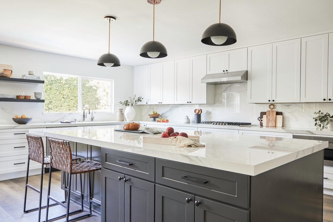 Modern kitchen with white shaker cabinets and a dark island, designed by a kitchen cabinet supplier for clean, functional storage.