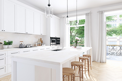 Bright modern white kitchen with Kitchen Cabinet Mississauga style cabinetry, a large white island, wood stools, pendant lights, and floor-to-ceiling windows.