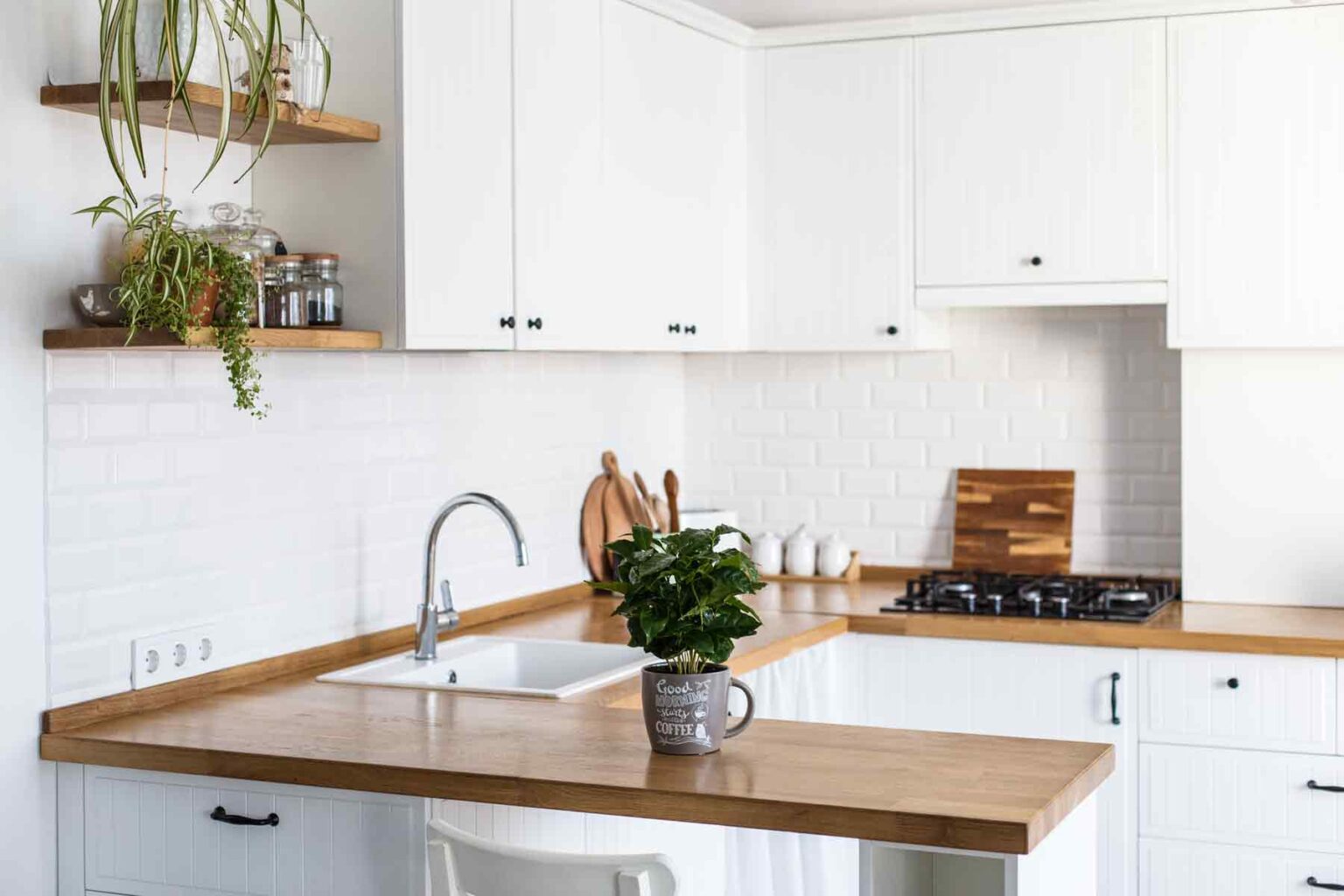 Bright white shaker-style kitchen with warm wood countertops, open shelves, subway tile backsplash, and black hardware — low price kitchen cabinet inspiration.