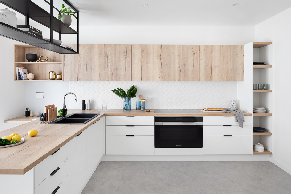 Modern L-shaped kitchen with white base units and natural wood uppers, featuring a Flat pack kitchen cabinet layout, open shelving, and a minimalist backsplash.