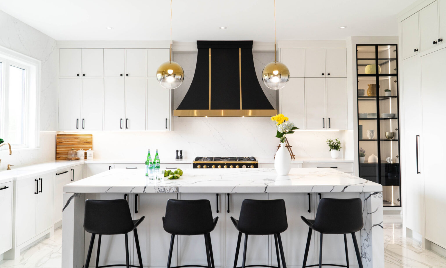Modern Kitchen cabinet design with white shaker cabinets, a black-and-brass range hood, and a marble waterfall island with black bar stools.
