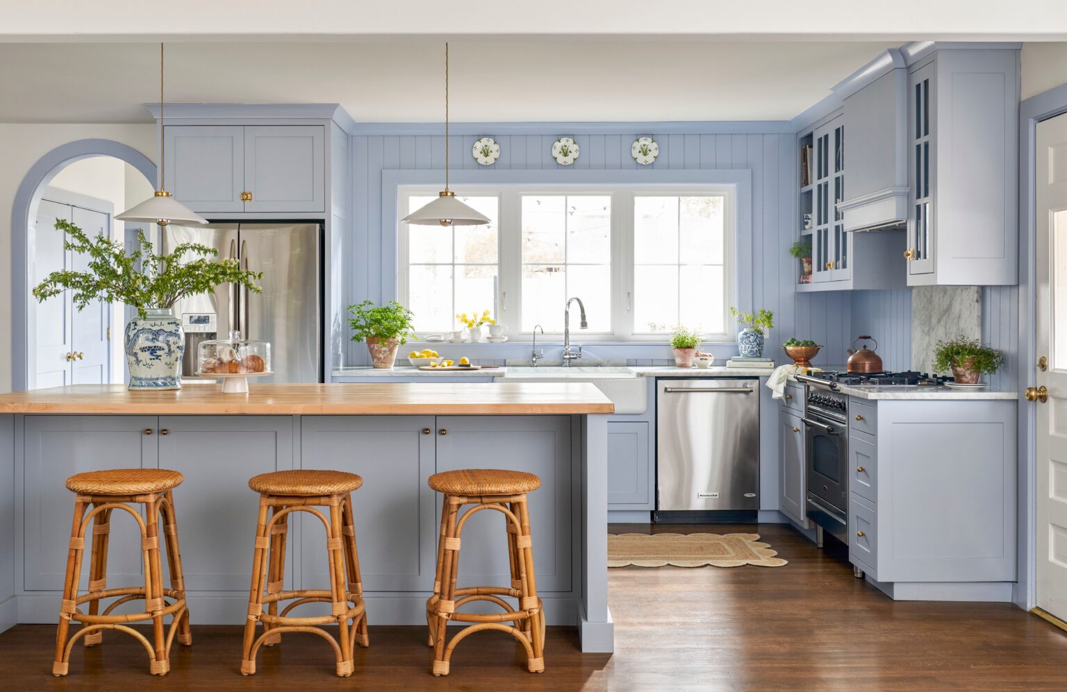 Premade kitchen cabinet set in soft blue shaker style with a wood-top island, farmhouse sink, and stainless steel appliances.