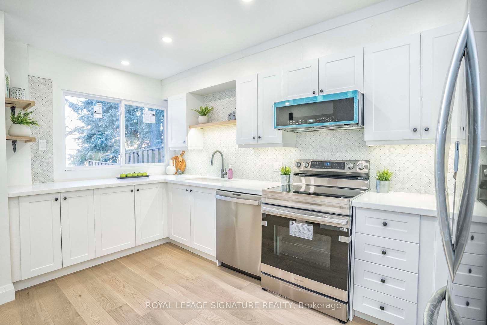 Kitchen cabinet Mississauga – bright modern white shaker cabinets with quartz countertops, stainless steel appliances, and an L-shaped townhouse kitchen layout.
