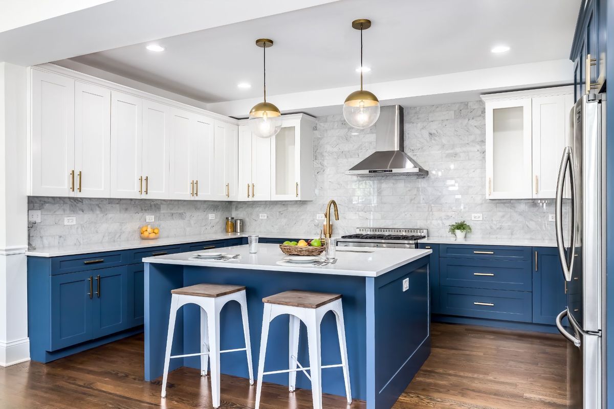 Kitchen cabinet Mississauga inspiration with navy blue base cabinets, white upper cabinets, marble backsplash, and a large island with seating.