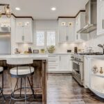 Modern white Kitchen cabinet Mississauga design featuring shaker-style cabinets, a large island with seating, quartz countertops, and stainless steel appliances in a bright Canadian home.
