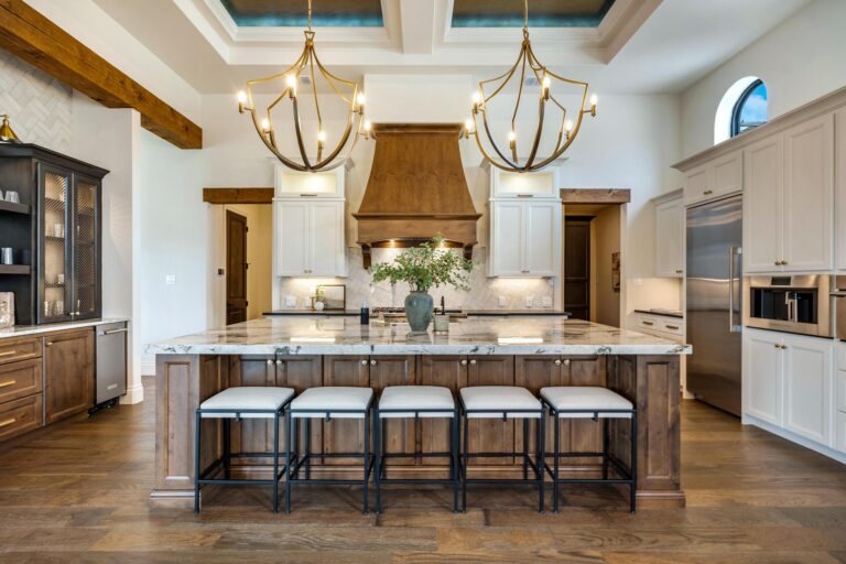 Luxury kitchen designed by a professional kitchen cabinet supplier, featuring a large wood island, white cabinetry, marble countertop, and elegant pendant lighting.