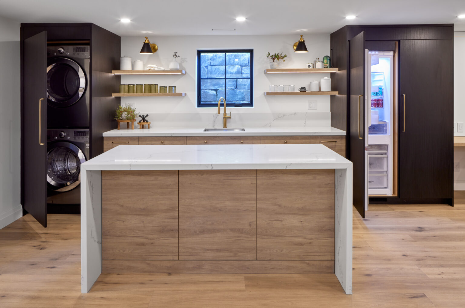 Modern two-tone Kitchen cabinet Mississauga setup with tall black cabinets, warm wood island, white quartz waterfall countertop, open shelves, and an integrated fridge.
