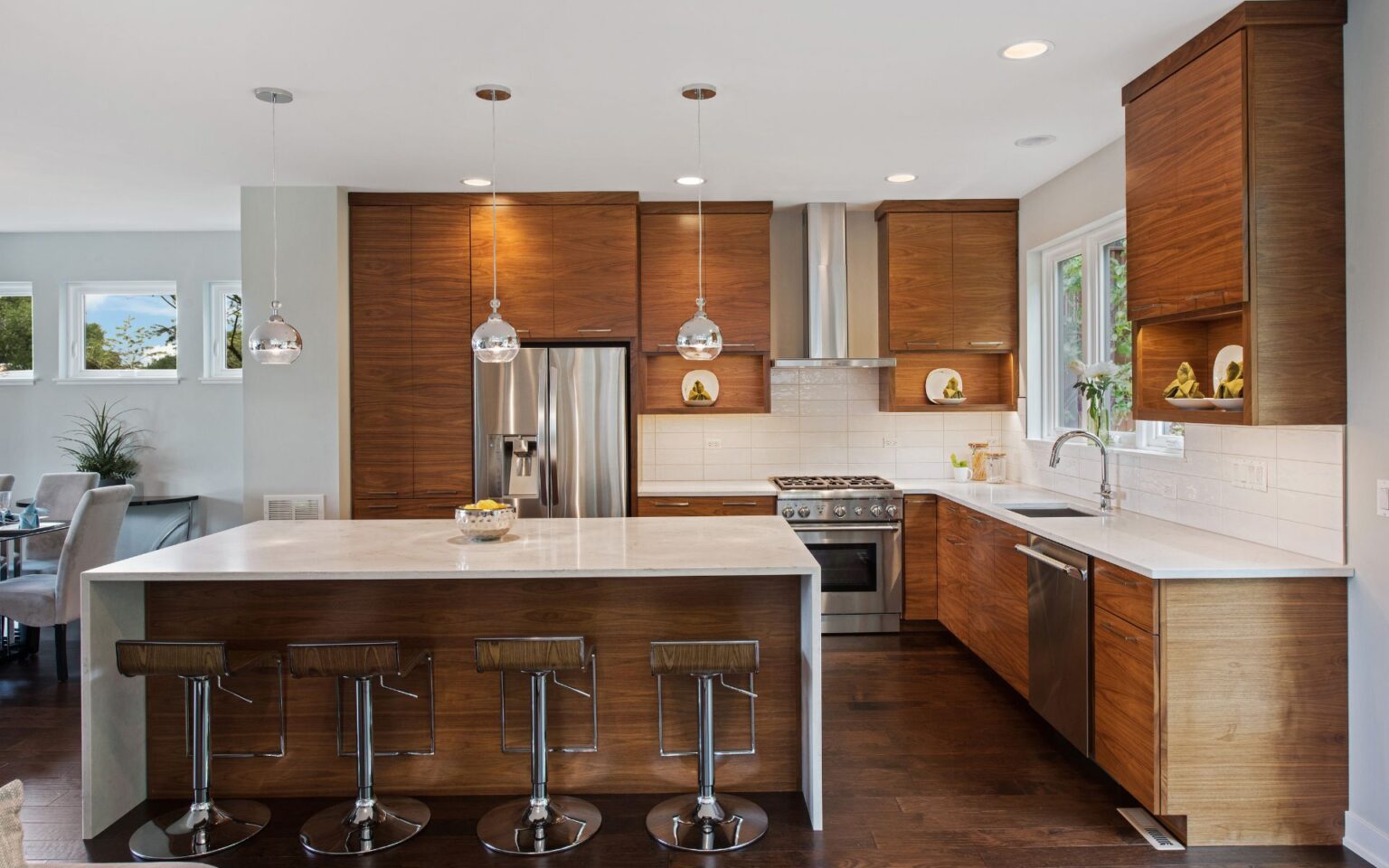 Modern kitchen featuring walnut-finish premade kitchen cabinets, a large white quartz island, built-in stainless steel appliances, and clean contemporary lighting.
