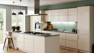 Modern minimalist kitchen featuring a flat pack kitchen cabinet system with white handleless doors, a large island, dark countertop, and soft green backsplash.
