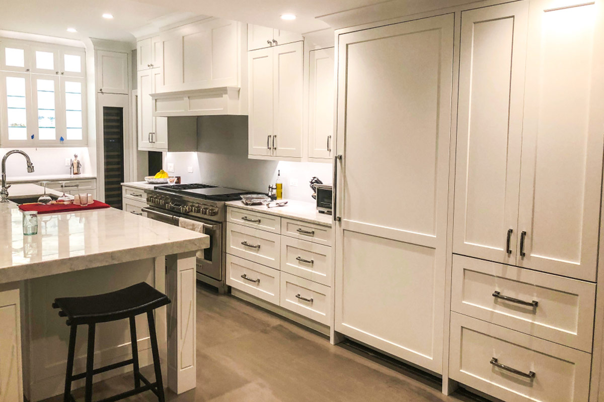 Modern white flat pack kitchen cabinet layout with full-height pantry units, shaker-style doors, and a large island in a bright contemporary kitchen