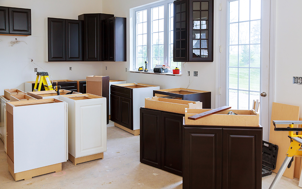 Flat pack kitchen cabinet installation in progress with assembled base cabinets and wall cabinets in a modern home renovation