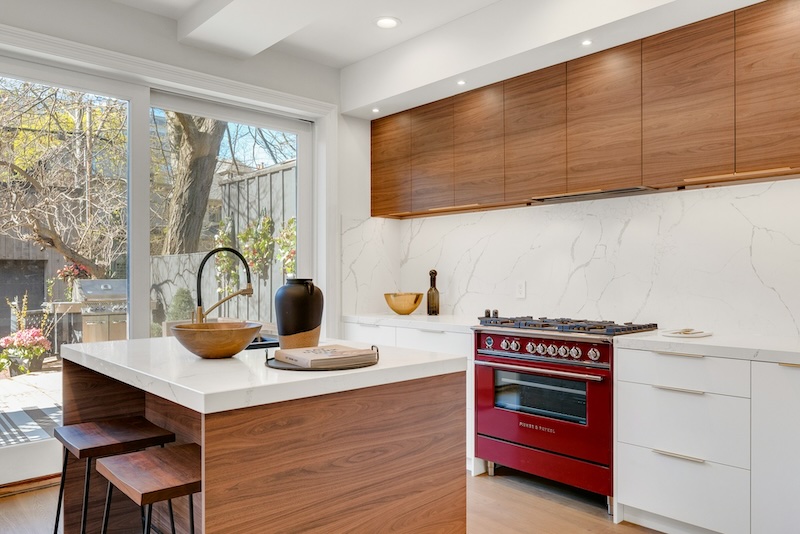 Modern kitchen with low price kitchen cabinet style—walnut flat-panel uppers, white base drawers, and a waterfall island with quartz countertop.