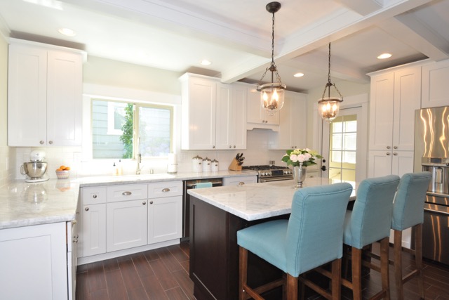 Kitchen cabinet supplier showcasing a bright white shaker-style kitchen with marble island, pendant lighting, and modern built-in cabinetry