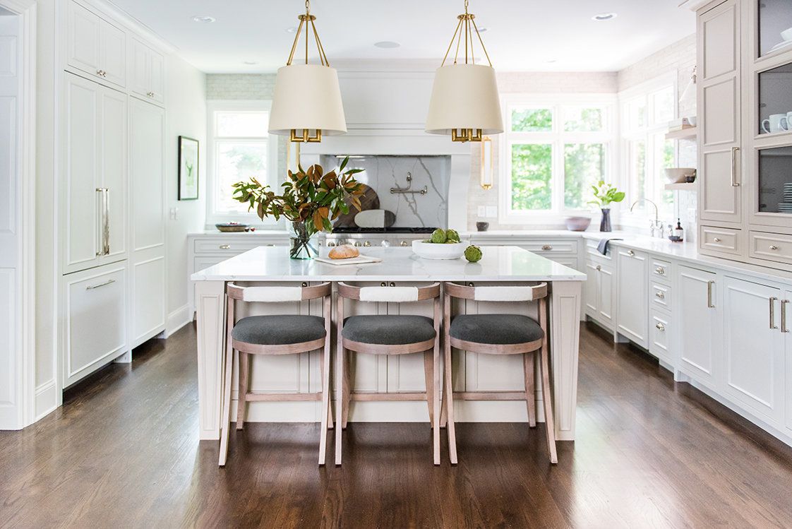 Low price kitchen cabinet set in a bright white kitchen with a large island, quartz countertop, and gold pendant lights.