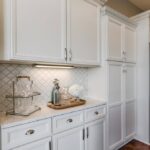 White shaker RTA kitchen cabinets with tall pantry cabinets, marble-look countertop, and under-cabinet lighting