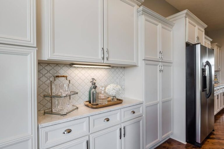 White shaker RTA kitchen cabinets with tall pantry cabinets, marble-look countertop, and under-cabinet lighting