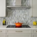 Kitchen cabinet design standards example with shaker cabinets, mosaic backsplash, and stainless range hood