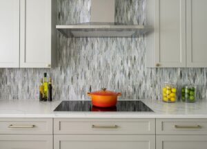 Kitchen cabinet design standards example with shaker cabinets, mosaic backsplash, and stainless range hood
